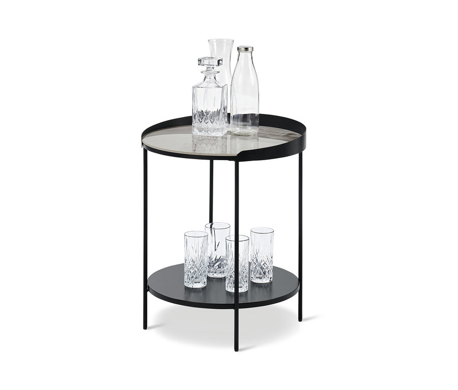 Auf der unteren Ablagefläche eines Beistelltisch mit Keramik-Tischplatte in Mamoroptik stehen vier Gläser, auf der oberen Ablagefläche eine Karaffe und zwei Gläser.