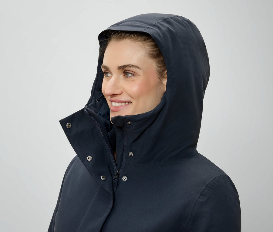 Frau mit Kapuze und dunkelblauer Jacke schaut nach rechts.