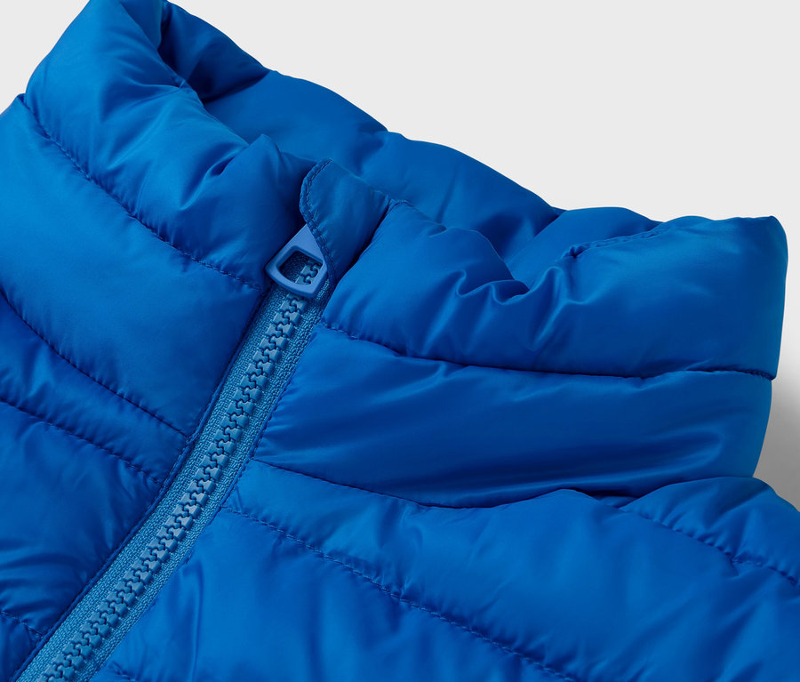 Detailaufnahme einer gesteppten, blauen Jacke mit Kragen und Reißverschluss.