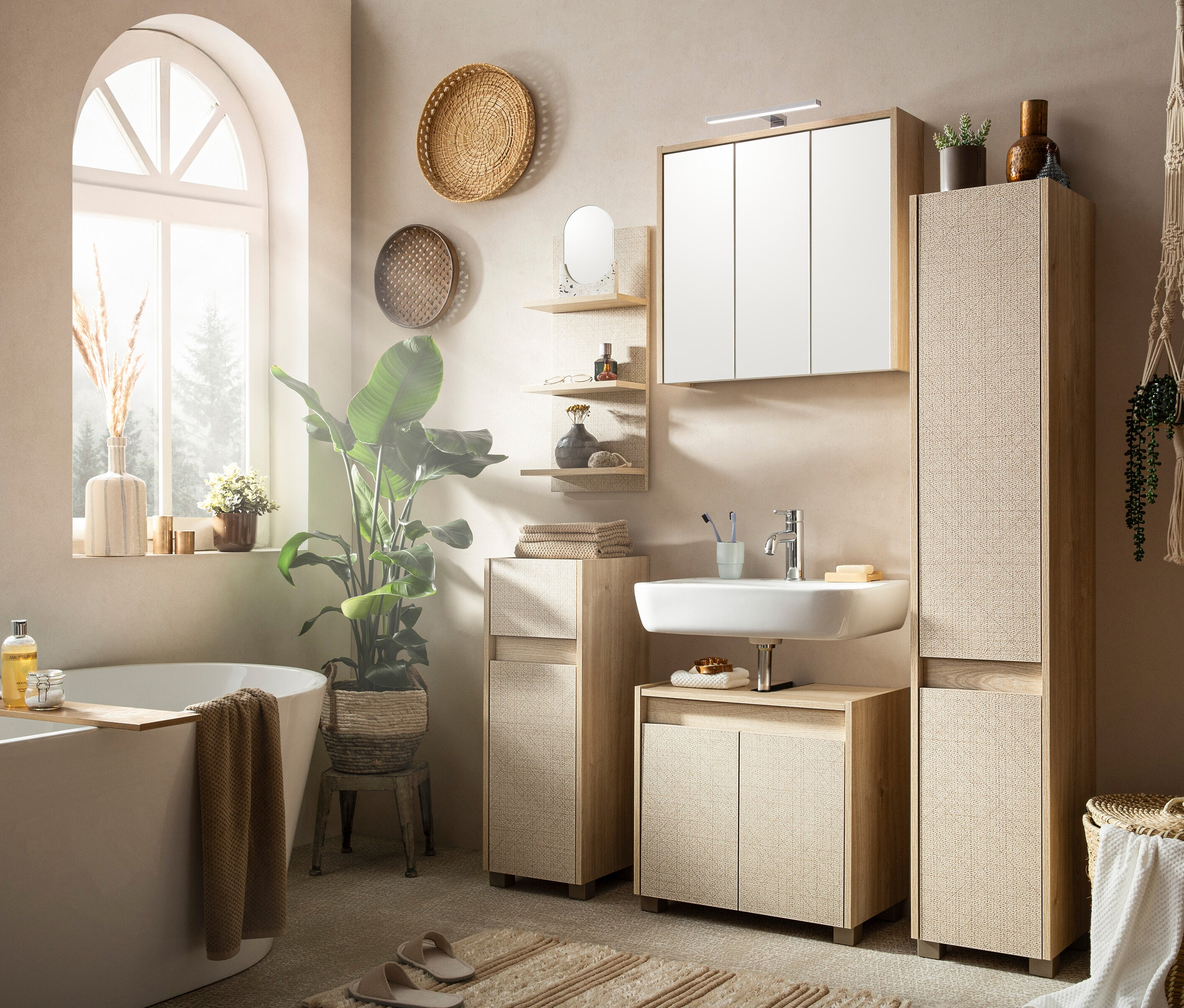 Badezimmer mit Badewanne, Waschbecken und hellen Stauraummöbeln.