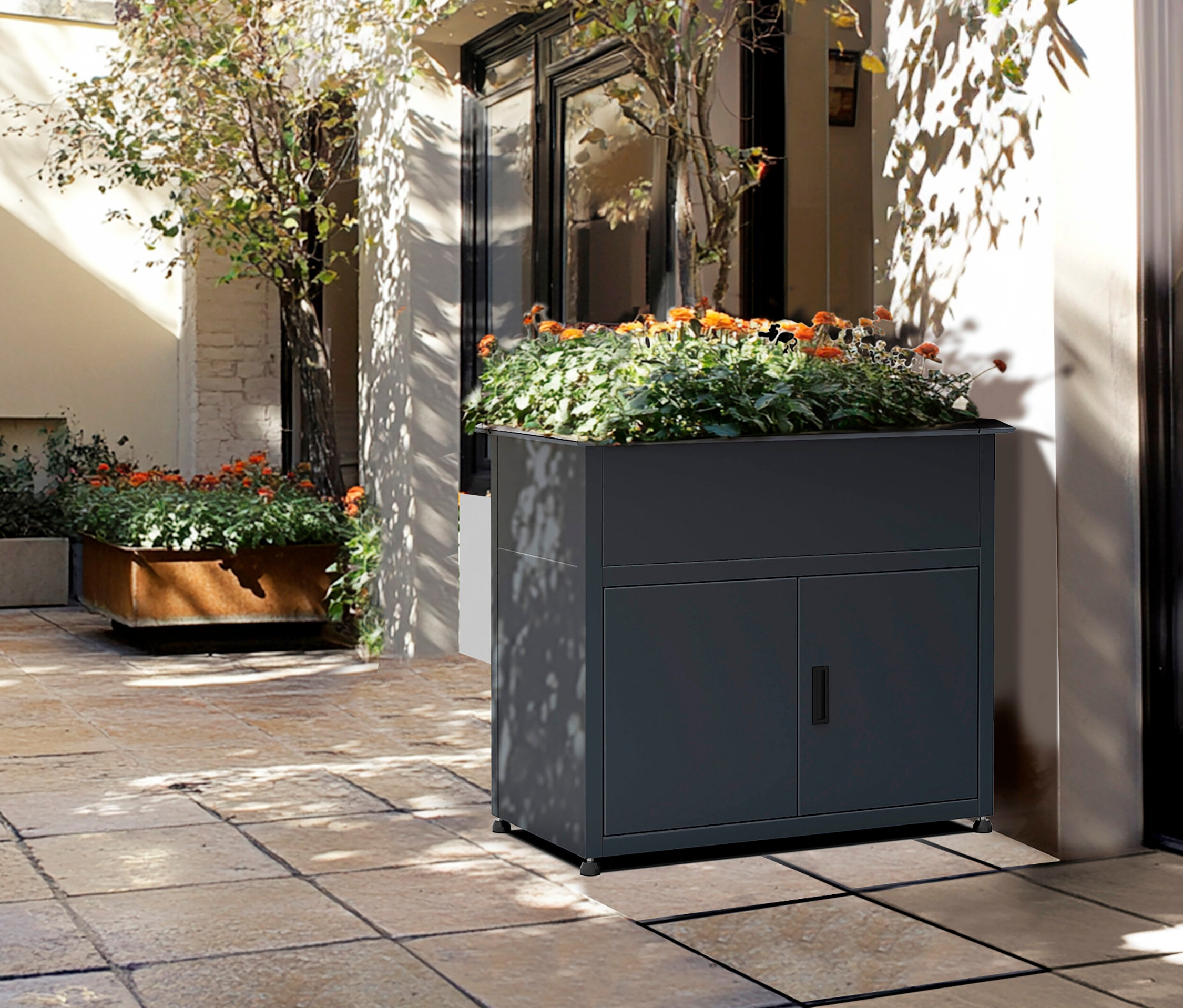 Dunkelgrauer Pflanzkasten mit Schranktüren steht auf einer Terrasse neben einem Hauseingang.