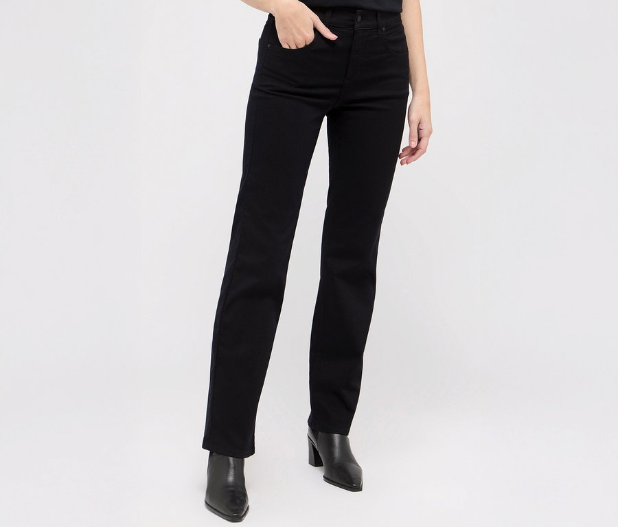 Eine Frau posiert in schwarzen Angels Denim »Lara« Straight Fit Jeans und schwarzen Stiefeletten.