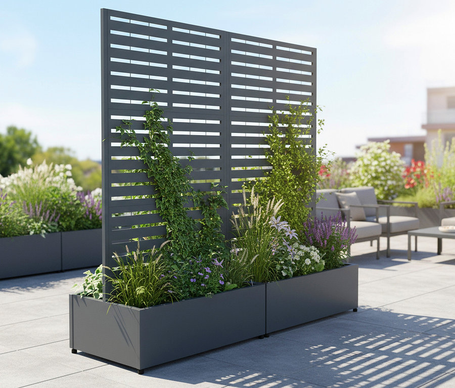 Außenansicht eines grauen Pflanzkastens mit verschiedenen Pflanzen und einem grauen Sichtschutz im Hintergrund.