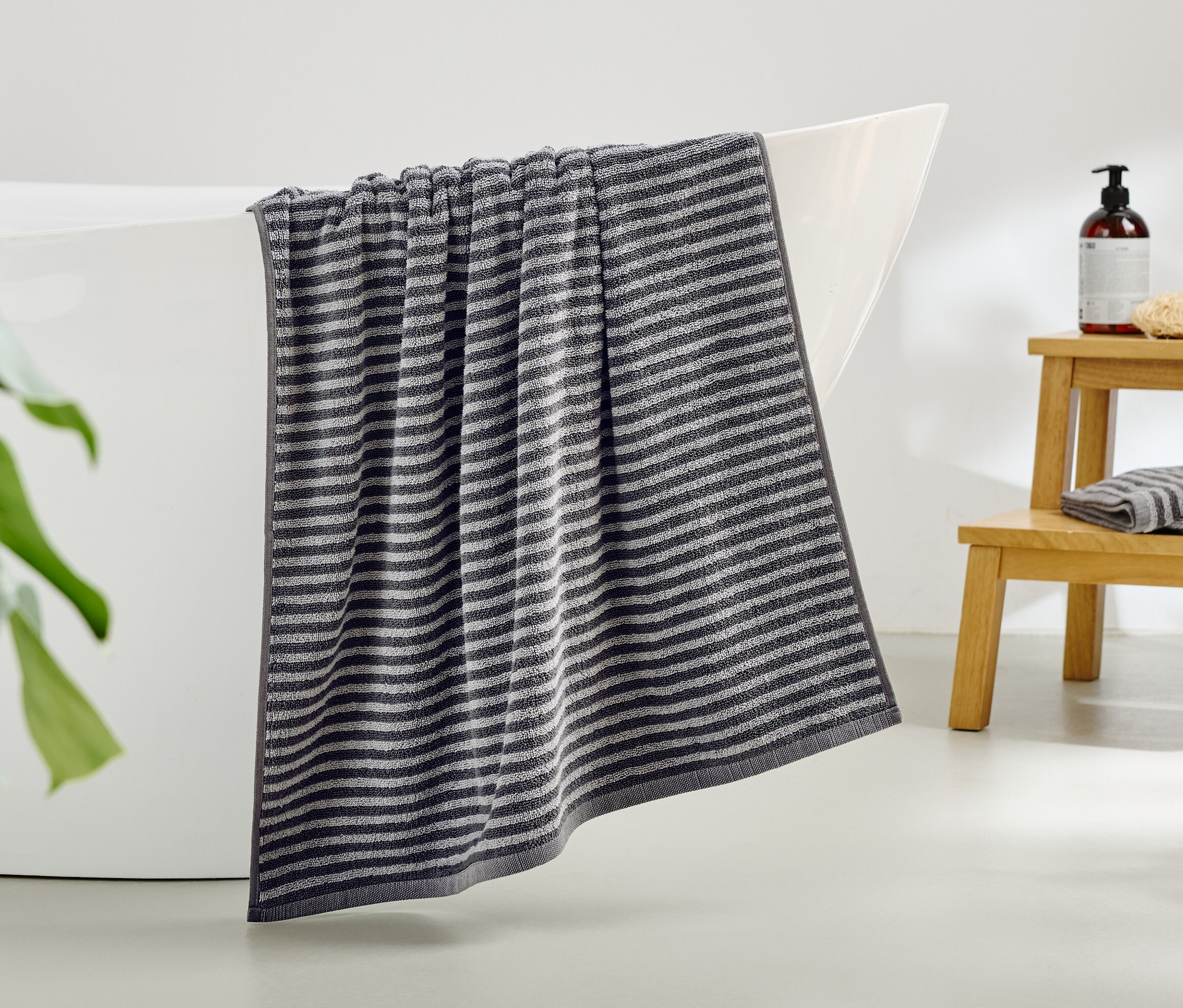 Ein gestreiftes Handtuch hängt über dem Rand einer Badewanne.