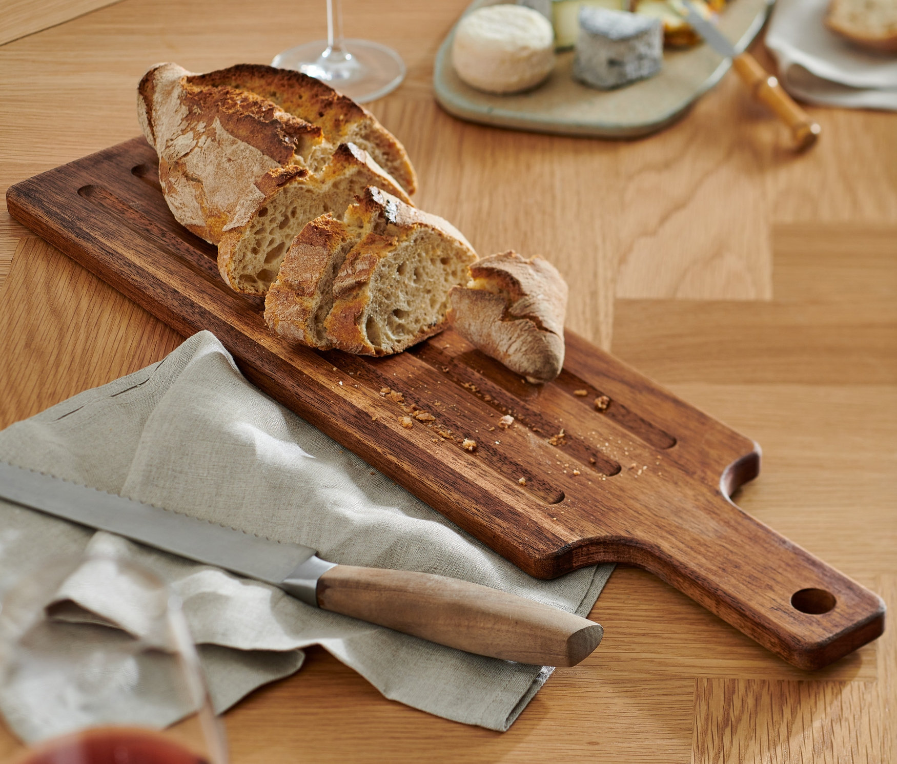 Brot auf einem Schneidebrett mit Messer und Glas Rotwein.