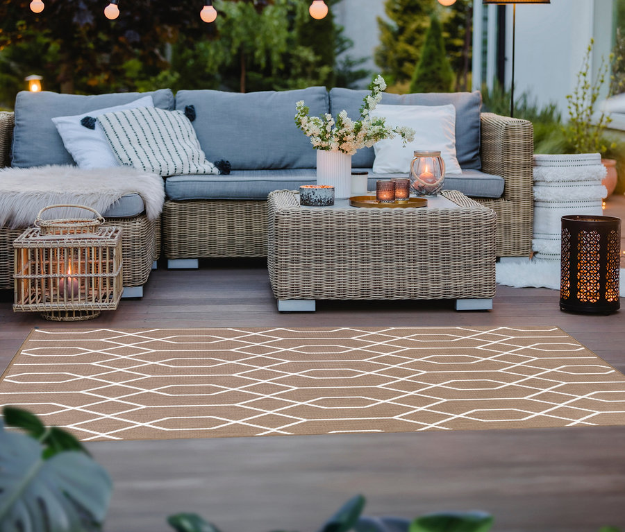 Eine Außenterrasse mit braunem Outdoor-Wende Teppich "Geo River" in 120 x 160 cm und 160 x 220 cm, einer Rattan-Couchgarnitur und Beleuchtung.