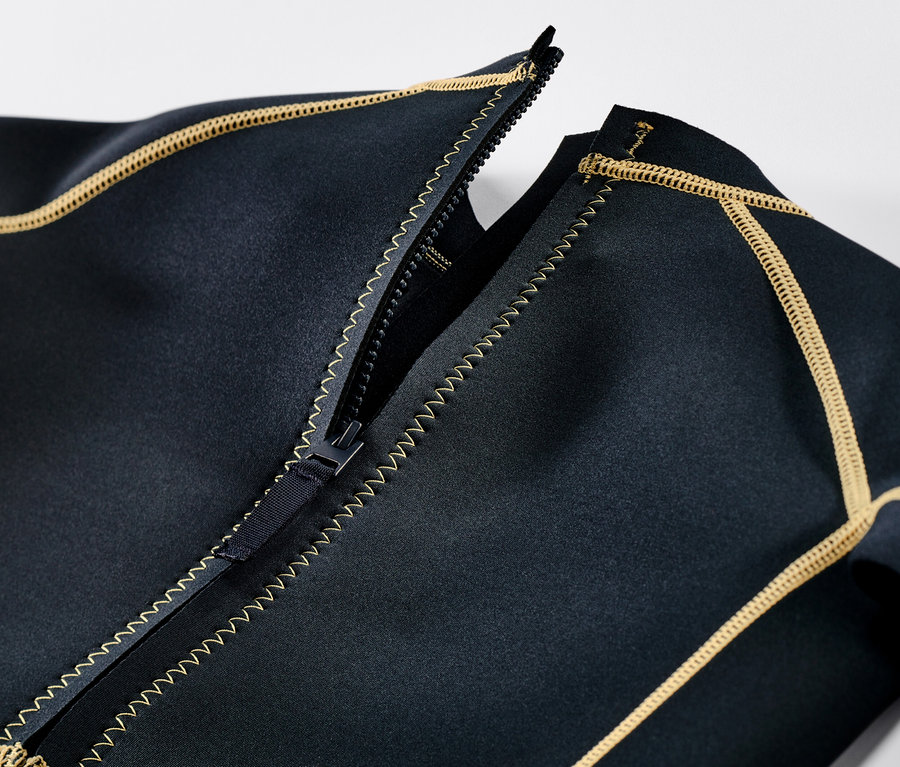 Detailansicht eines Kinder-Neoprenanzugs mit geöffnetem Reißverschluss und gelben Ziernähten.