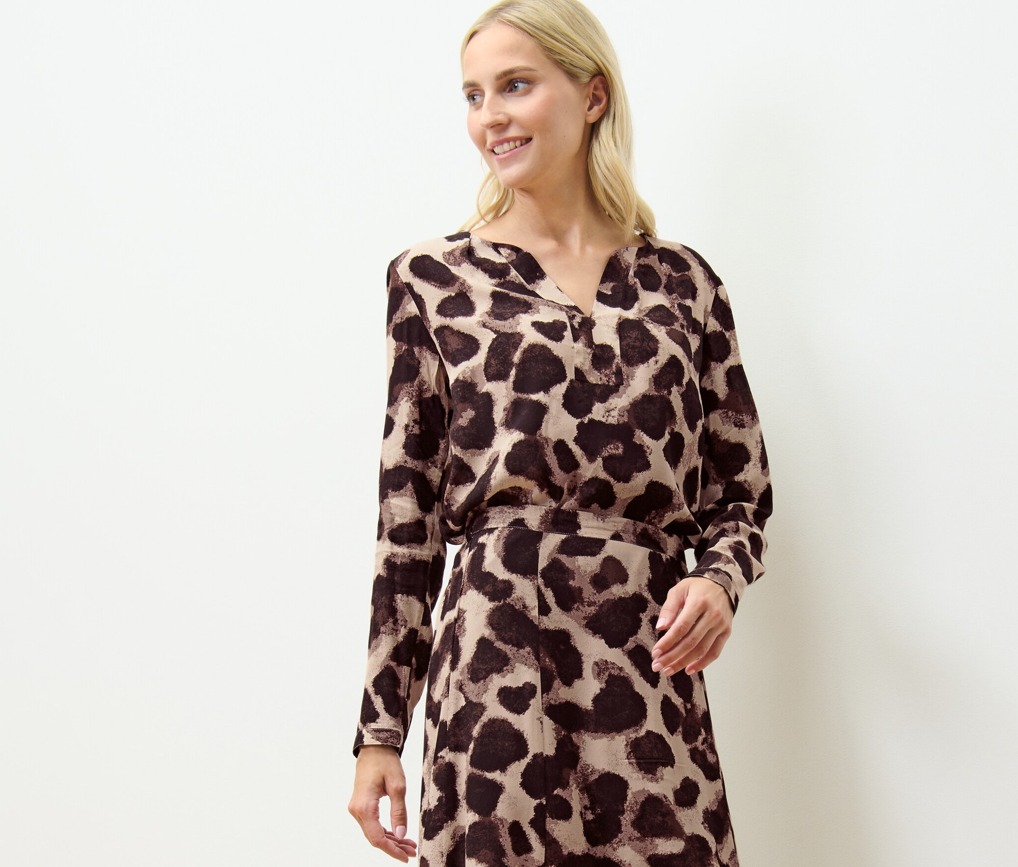 Blonde Frau trägt eine bedruckte Bluse.