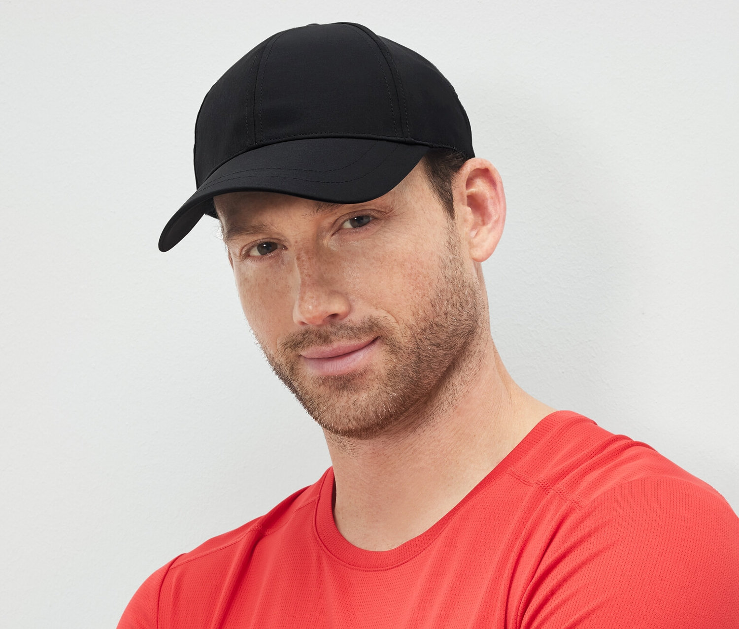 Mann mit verschränkten Armen trägt eine schwarze Sportkappe.