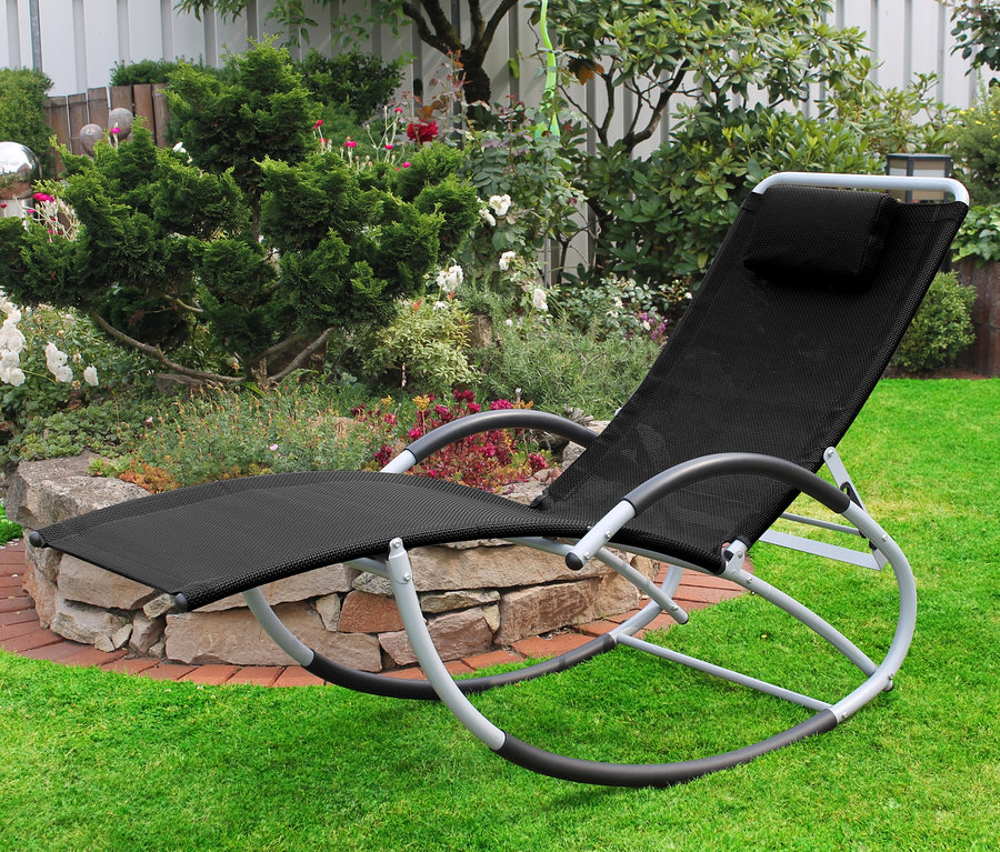 Eine anthrazitfarbene Schaukelliege mit verstellbarer Rückenlehne steht auf einer Wiese im Garten.
