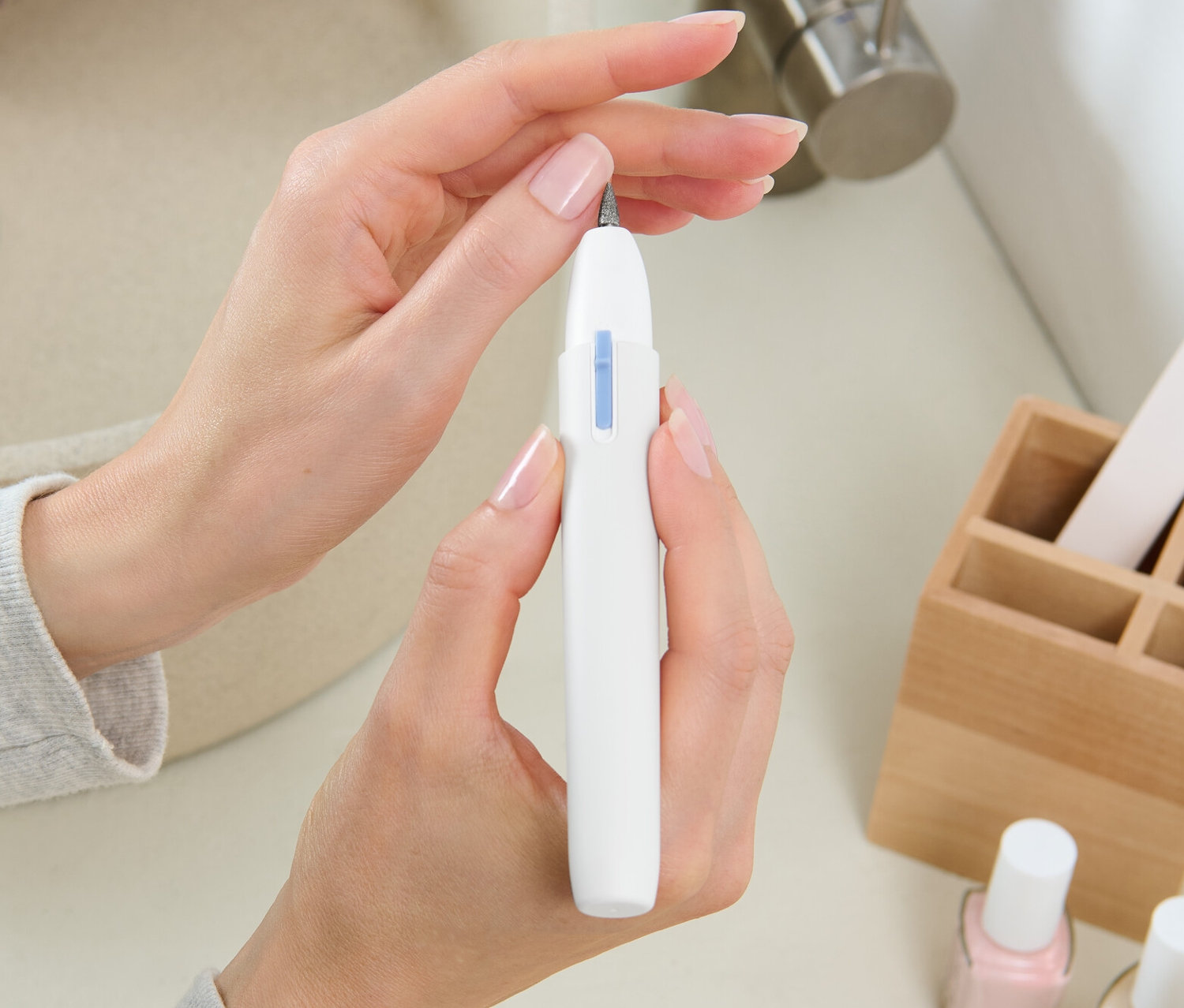 Frau hält Maniküre-und-Pediküre-Gerät in der Hand.