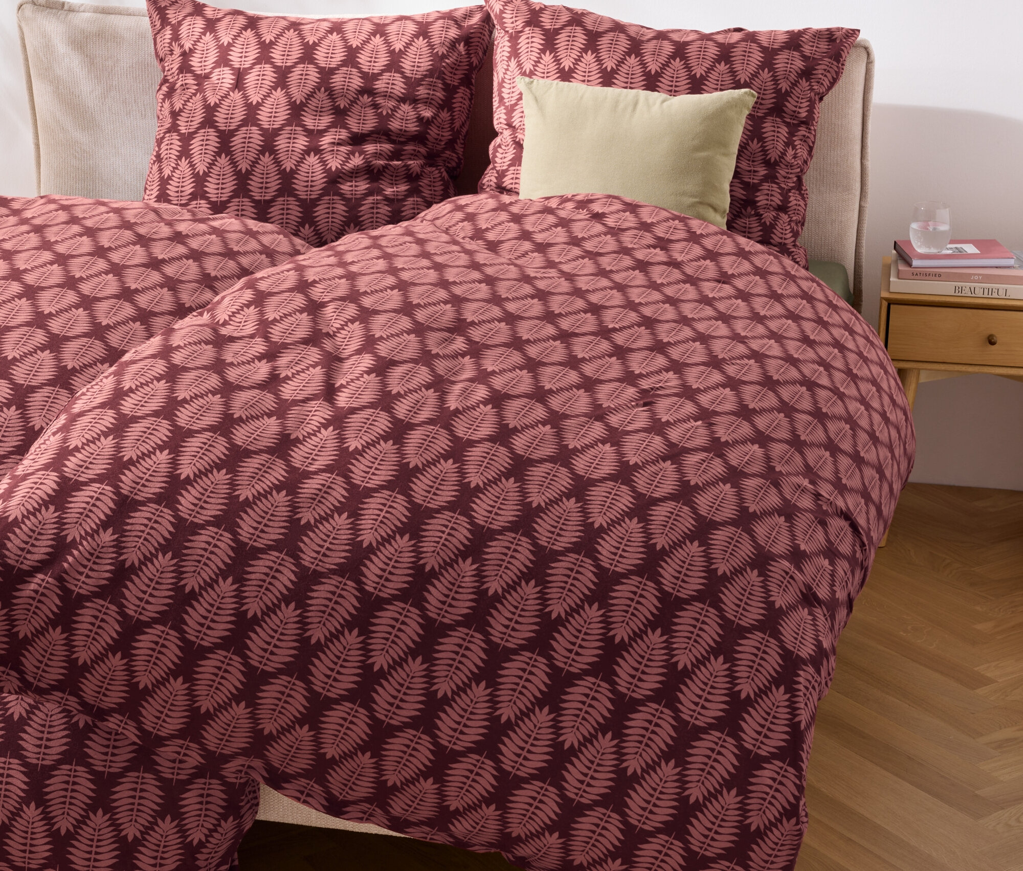 Nahaufnahme eines Bettes mit Winterjersey-Bettwäsche in Normalgröße und Übergröße mit Blattmuster.