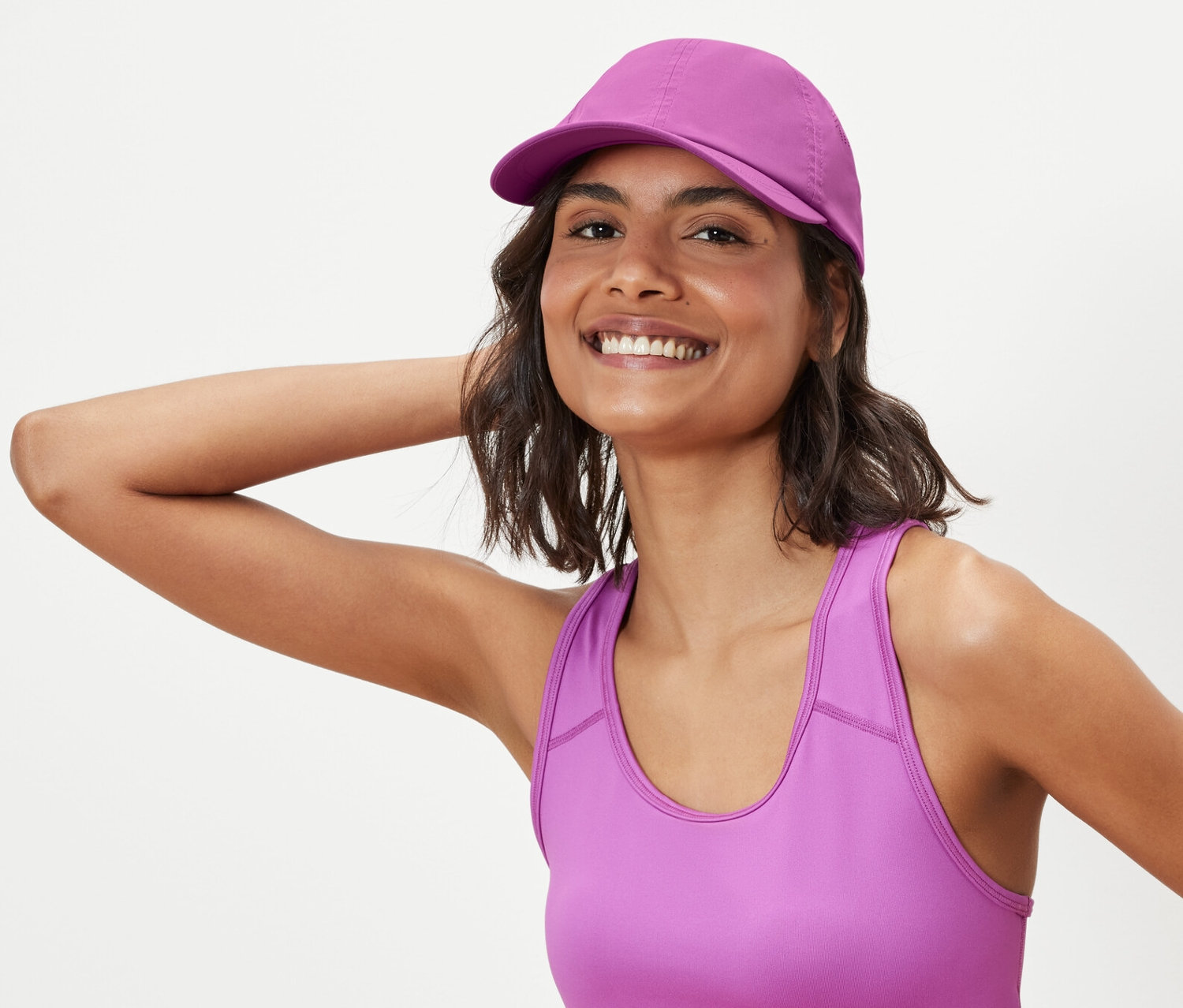 Frau posiert in Sport-BH und Sport-Kappe.