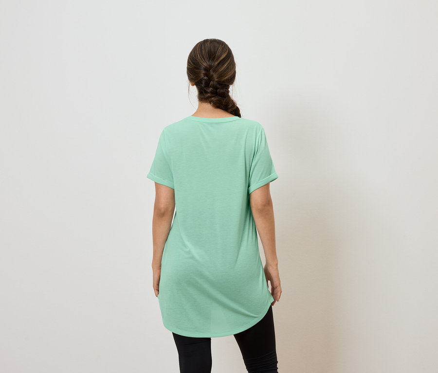 Frau mit dem Rücken zur Kamera trägt ein grünes T-Shirt und schwarze Leggings.