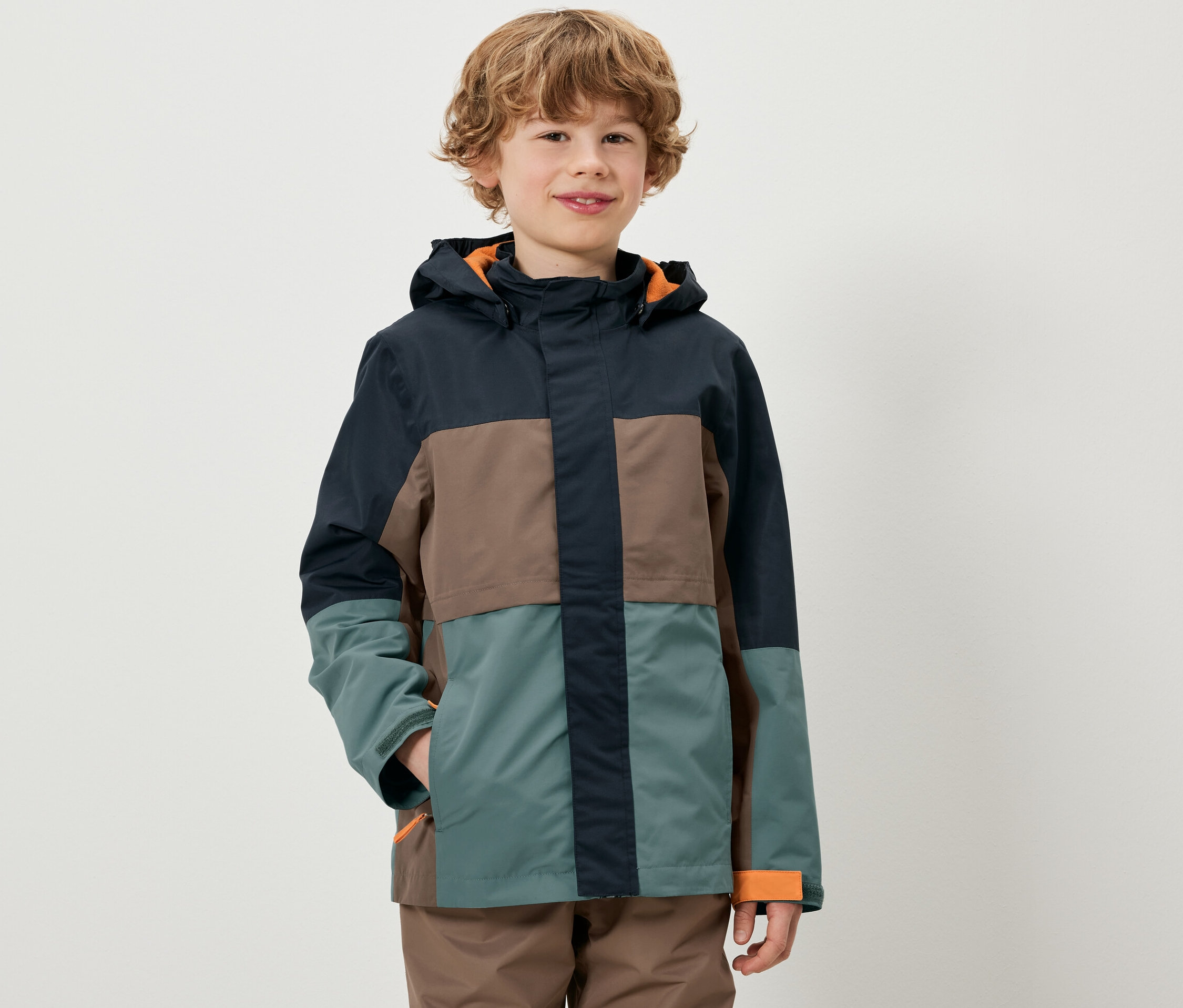 Ein Junge trägt eine farbenfrohe Kinder-Allwetterjacke.