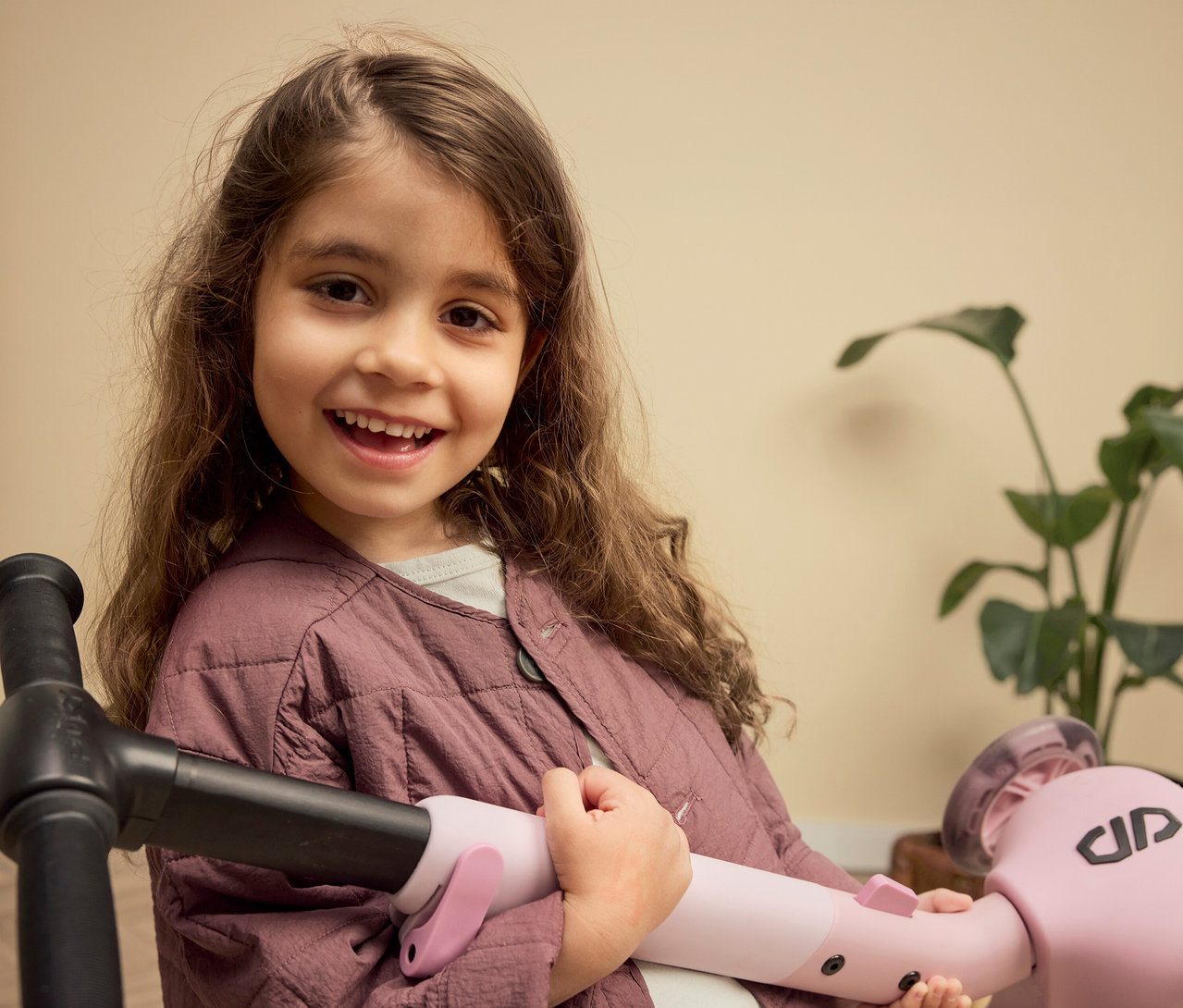 Lächelndes Mädchen hält einen rosa PUKY Roller PUSH vor sich.