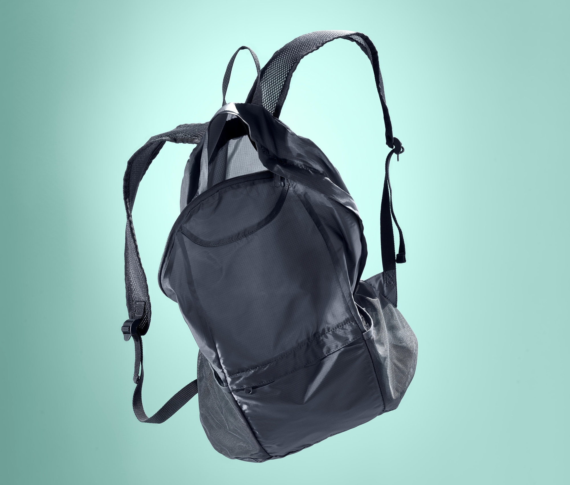 Schwarzer, faltbarer Rucksack vor türkisem Hintergrund.