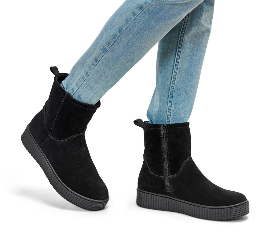 Beine in Jeans und Veloursleder-Boots.