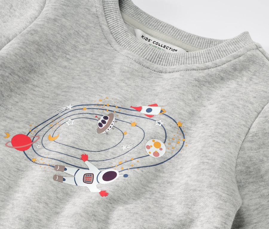 Detailansicht eines Kinder-Sweaters mit Weltraumaufdruck.