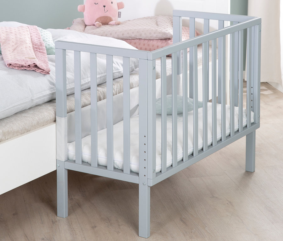 Graues roba 2-in-1-Beistellbett »safe asleep®«, taupe, steht neben einem großen Bett.