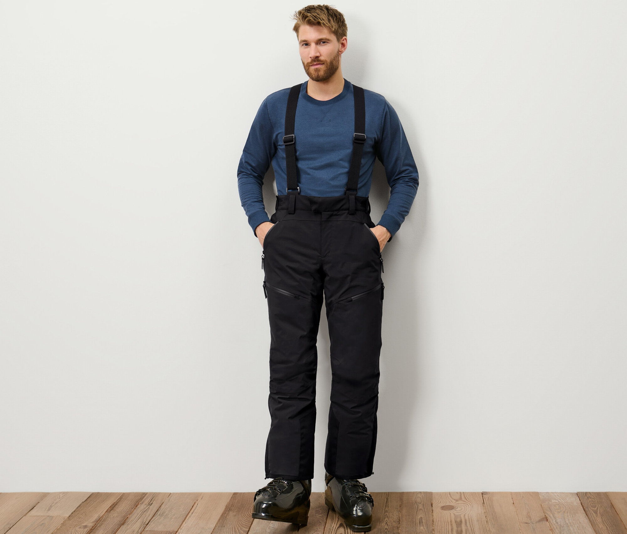 Mann steht mit Händen in den Taschen einer schwarzen High-Tech-Skihose.