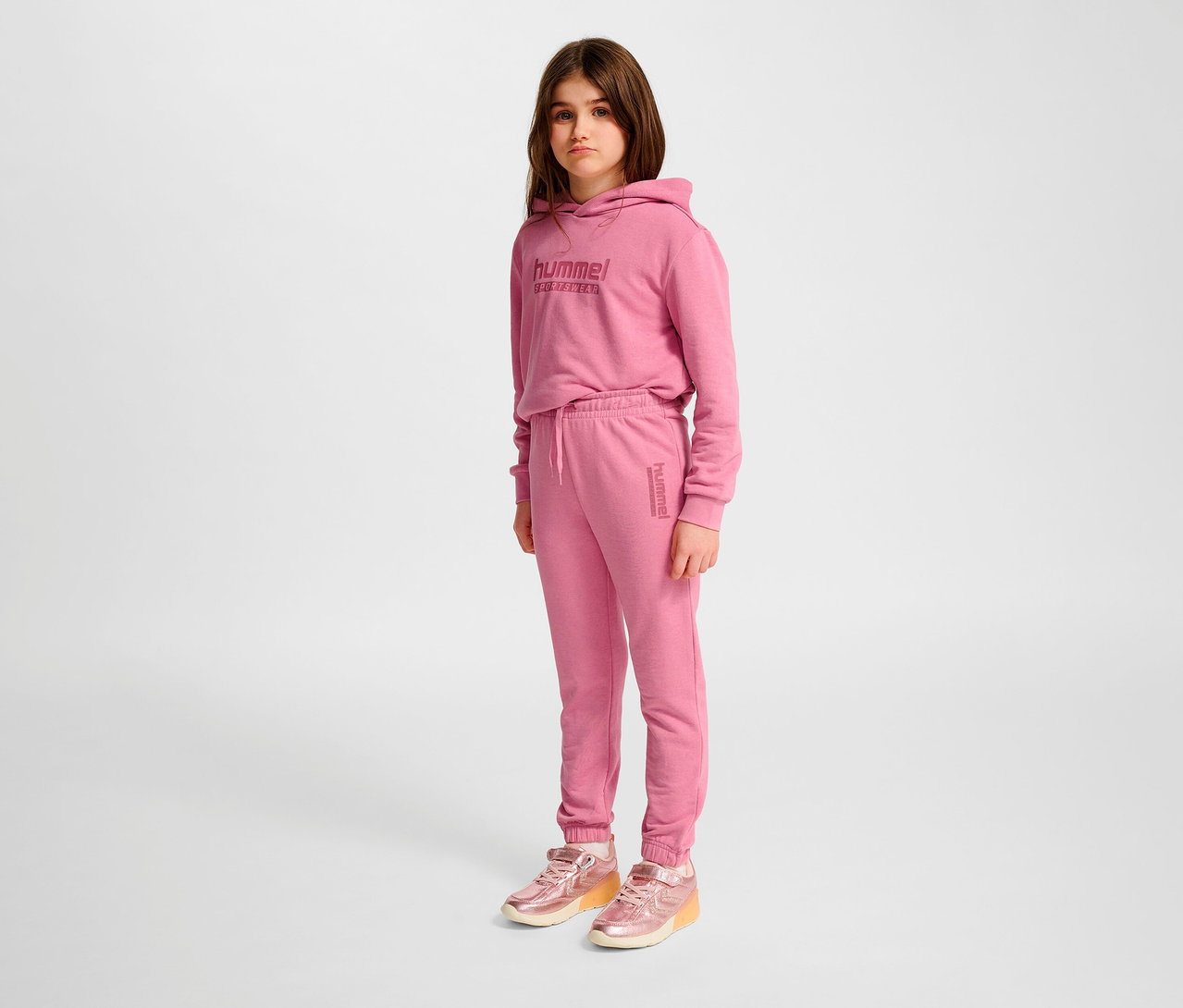 Mädchen trägt rosa HUMMEL HMLJR Base Regular Pants und Hoodie.