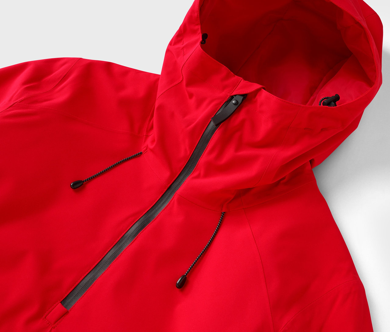 Detailaufnahme einer roten Kapuzenjacke mit schwarzem Reißverschluss.