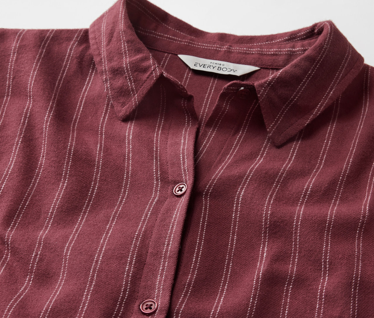 Detailansicht eines bordeauxroten, gestreiften Hemdes mit Kragen und Knöpfen.