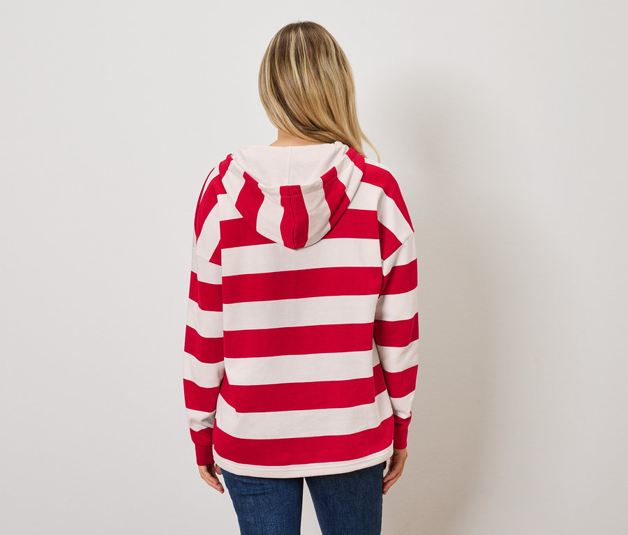 Frau mit dem Rücken zur Kamera trägt einen rot-weiß gestreiften Hoodie und blaue Jeans.