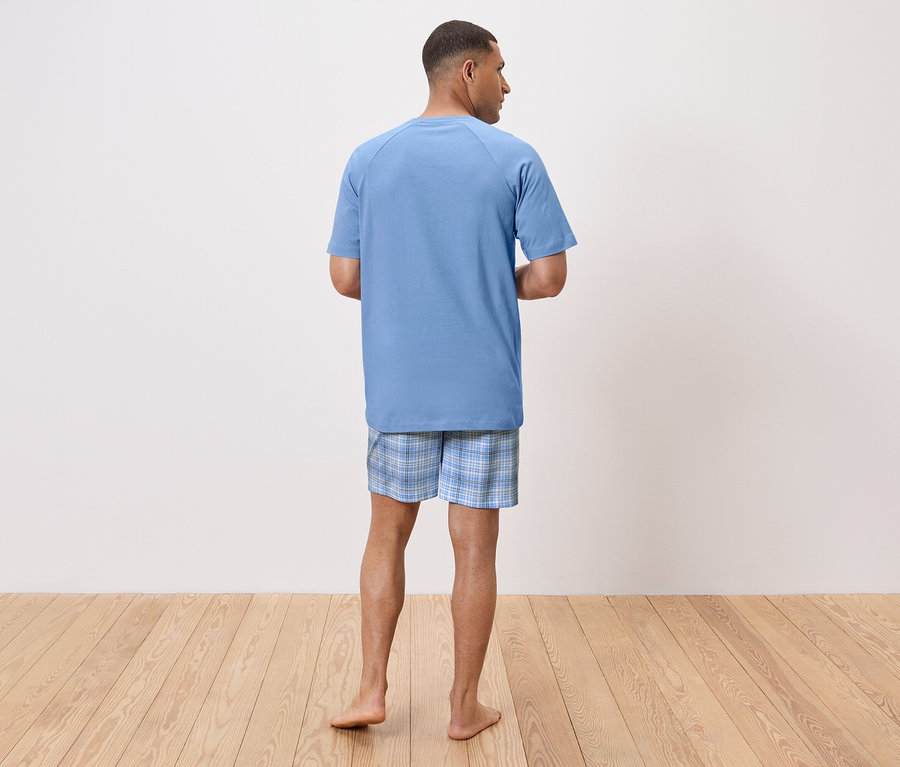 Mann von hinten trägt ein blaues Schlaf-T-Shirt und karierte Shorts.