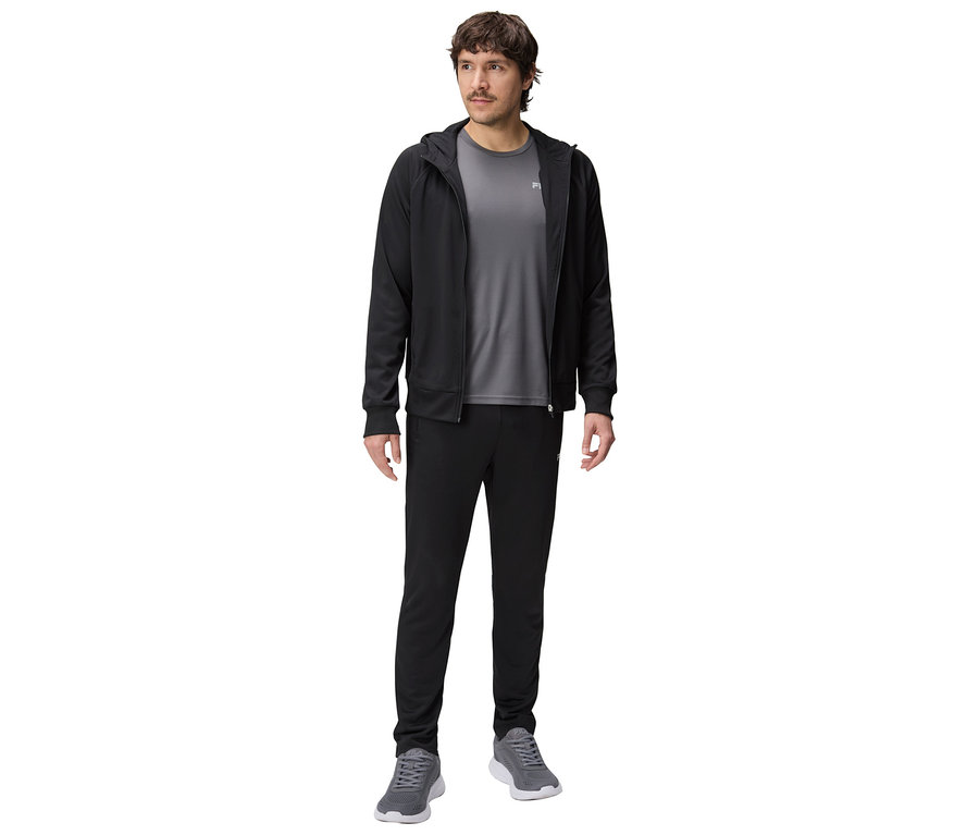 Mann in schwarzer Trainingsjacke mit Kapuze, grauem T-Shirt und schwarzen Trainingshosen, dazu graue Turnschuhe.