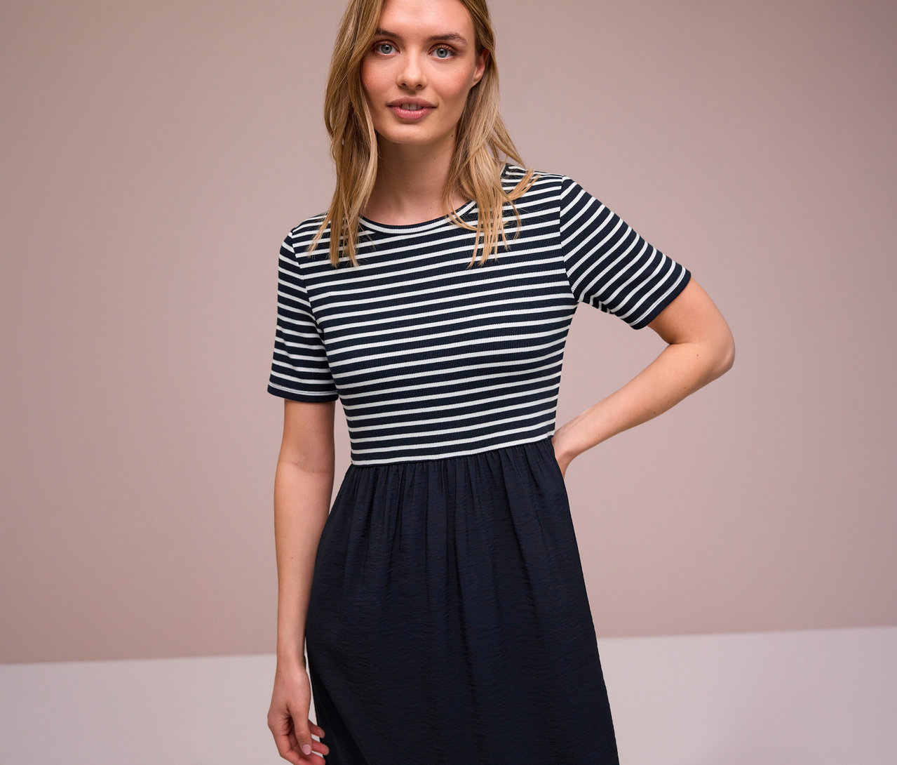 Frau mit gestreiftem Street One Kleid mit kurzem Arm und dunklem Rockteil.