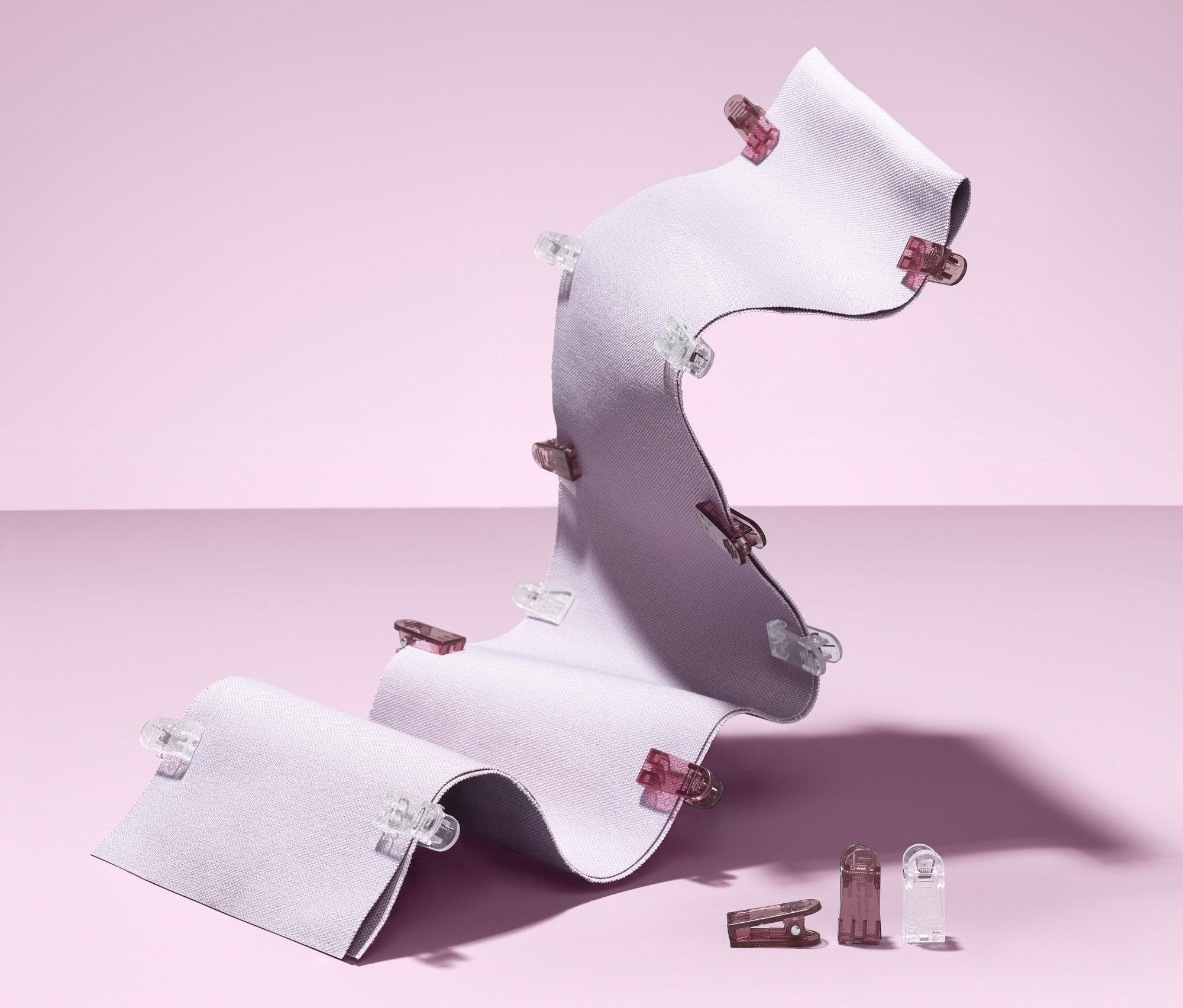 Ein gewelltes, weißes Stoffstück ist mit 20 Stoffklammern befestigt.