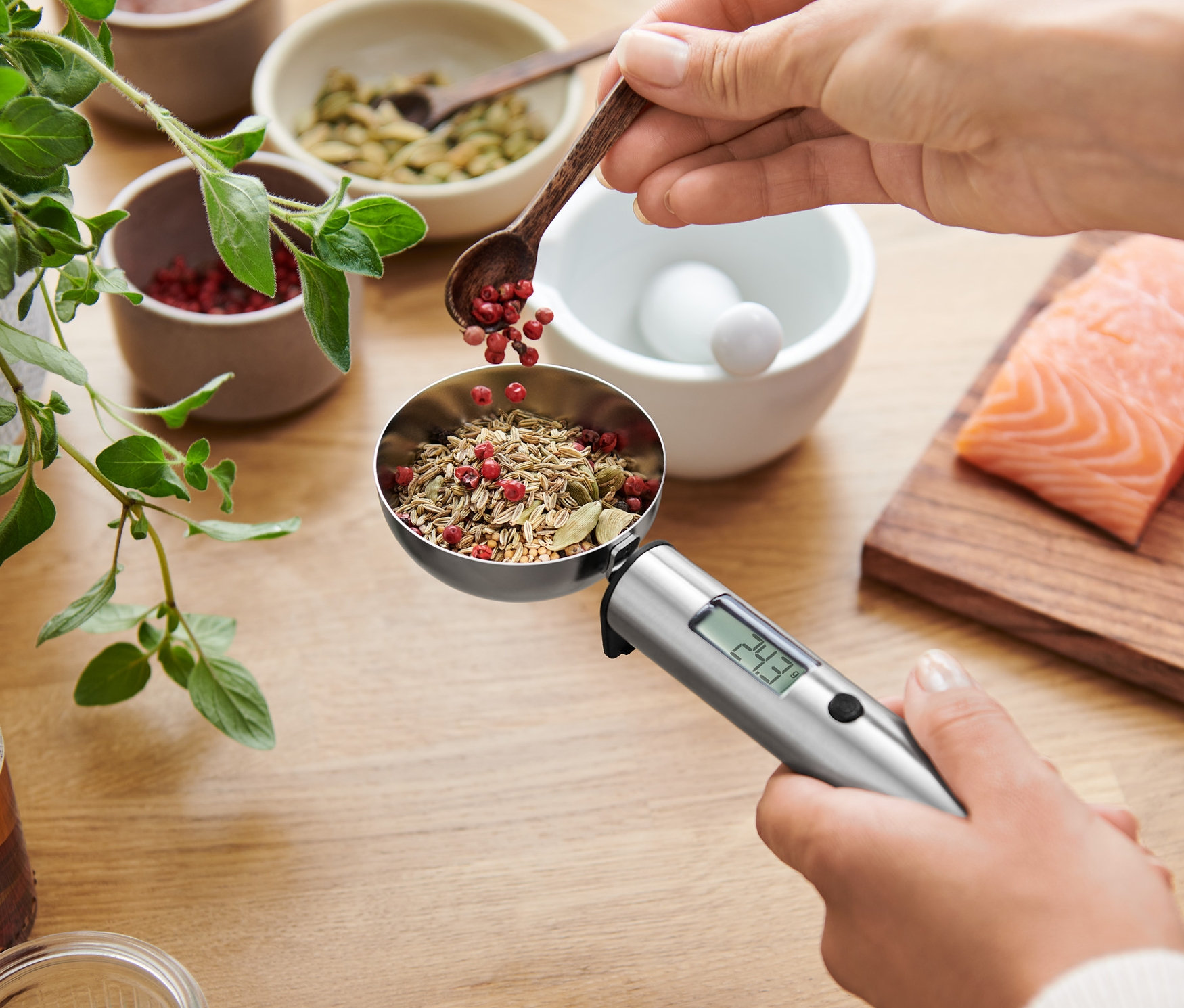 Frau gibt Gewürze in eine digitale Löffelwaage über zwei Lachsfilets.