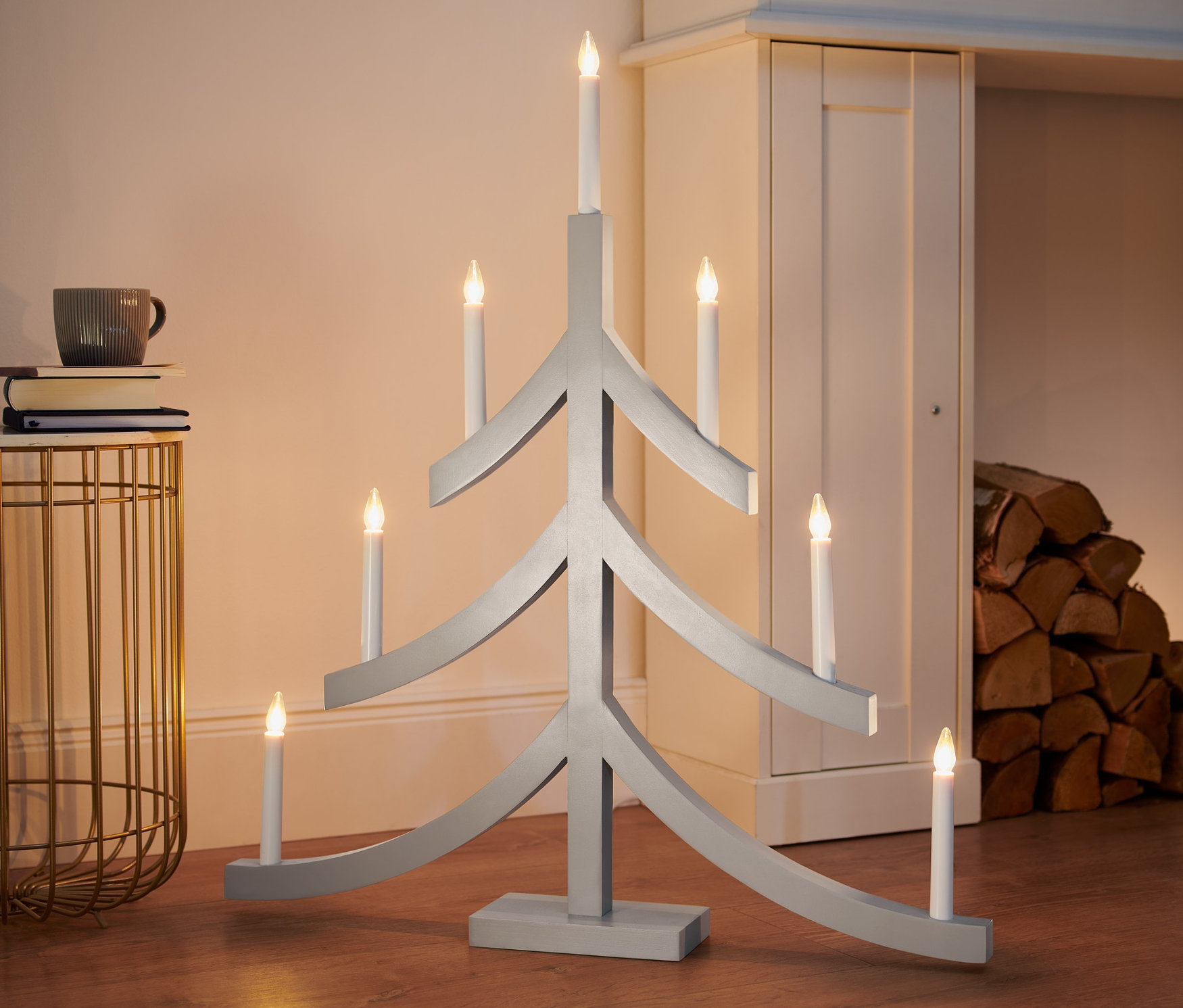 Ein grauer XL-LED-Kerzenleuchter in Form eines Weihnachtsbaums steht auf dem Boden.