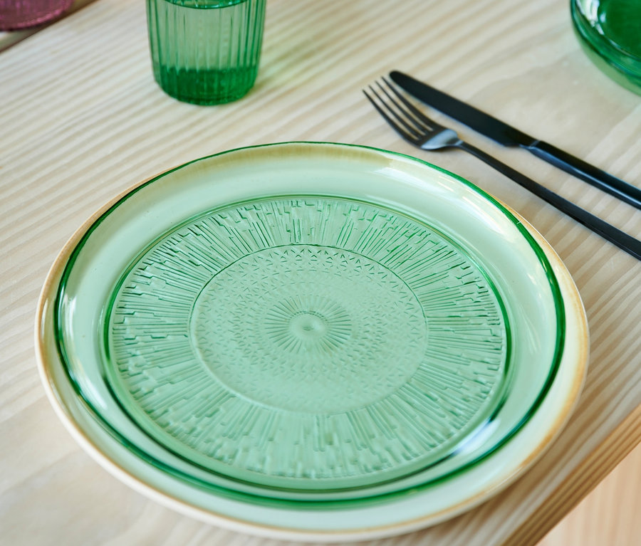 Zwei grüne Bitz Glasteller »Kusintha«, 25 cm, auf einem Tisch gestapelt.