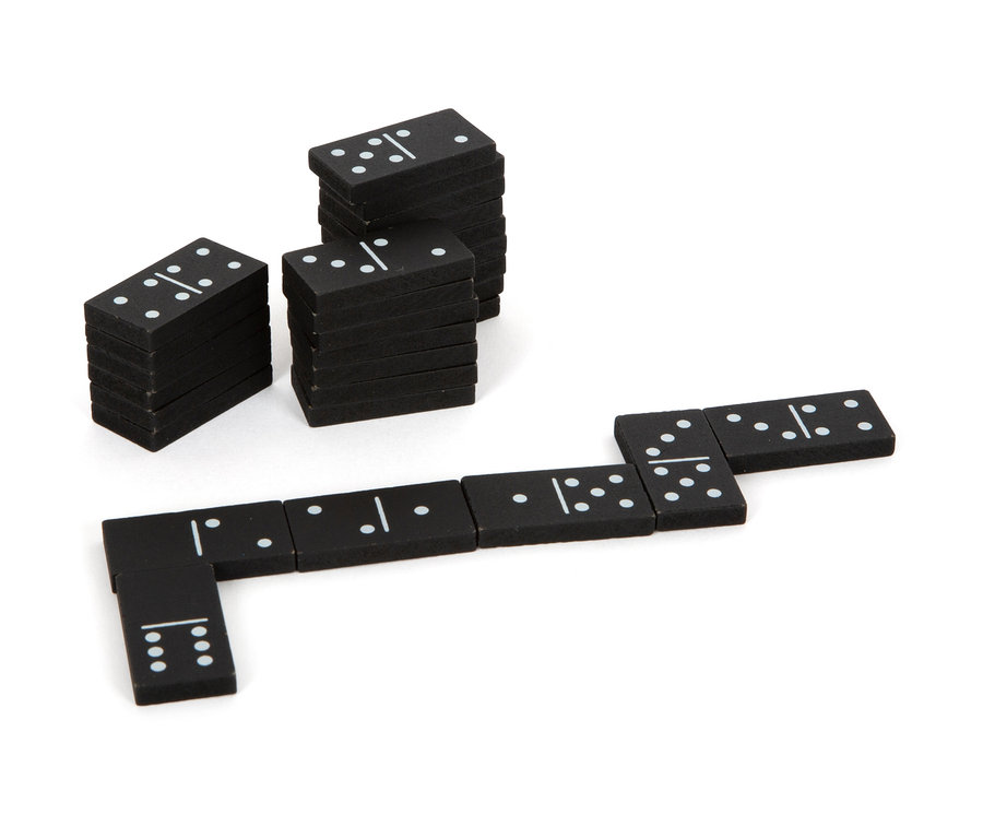 Schwarze Dominosteine aus der small foot Spielesammlung, gestapelt in Säulen und Reihe auf weißem Hintergrund.