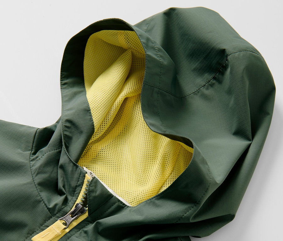 Detailaufnahme einer grünen Kinder-Sport-Funktionsjacke mit Kapuze und gelbem Reißverschluss.