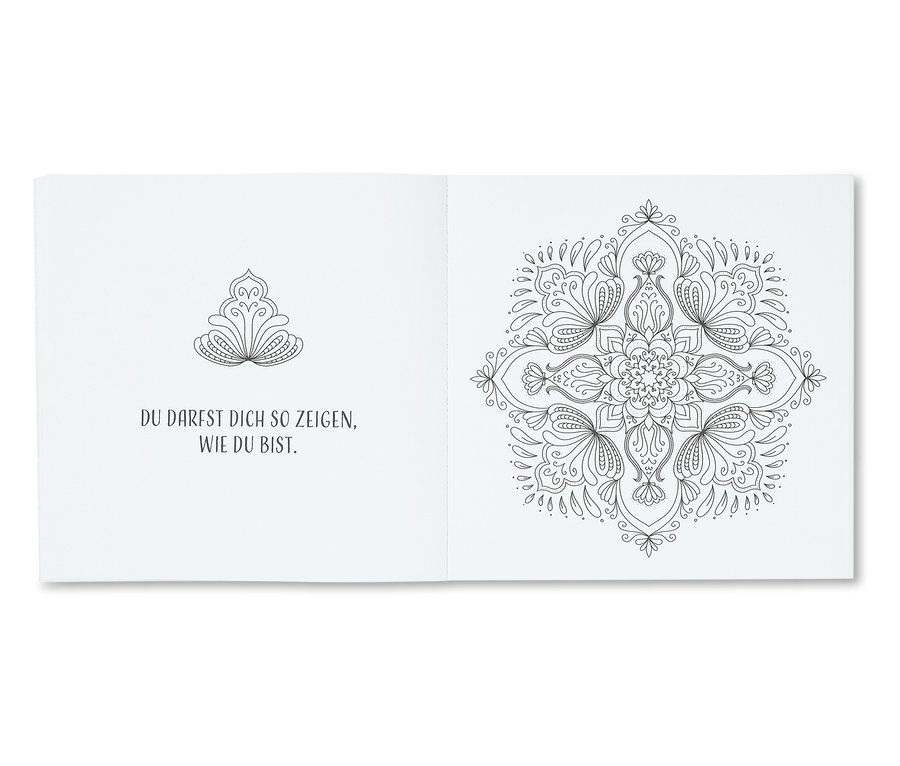 Ein offenes Buch mit schwarz-weißen Blumenmandalas und Text.