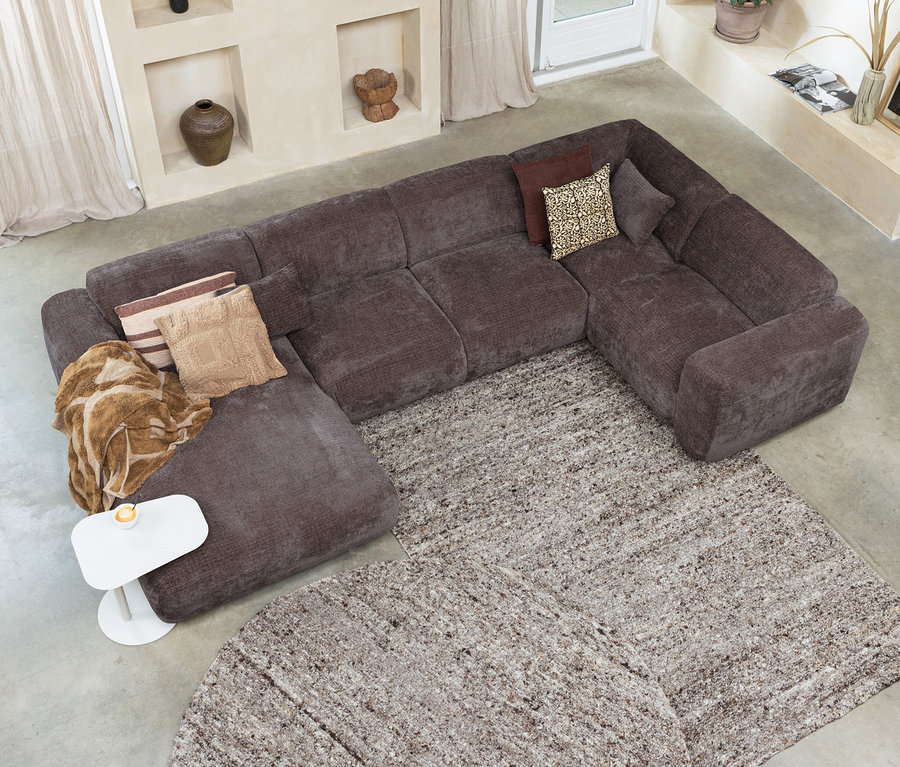 Draufsicht auf ein braunes Ecksofa mit Kissen und einem weißen Tisch auf einem beigen Boden, auf dem ein runder und ein rechteckiger Woood Teppich »Efia« liegen.