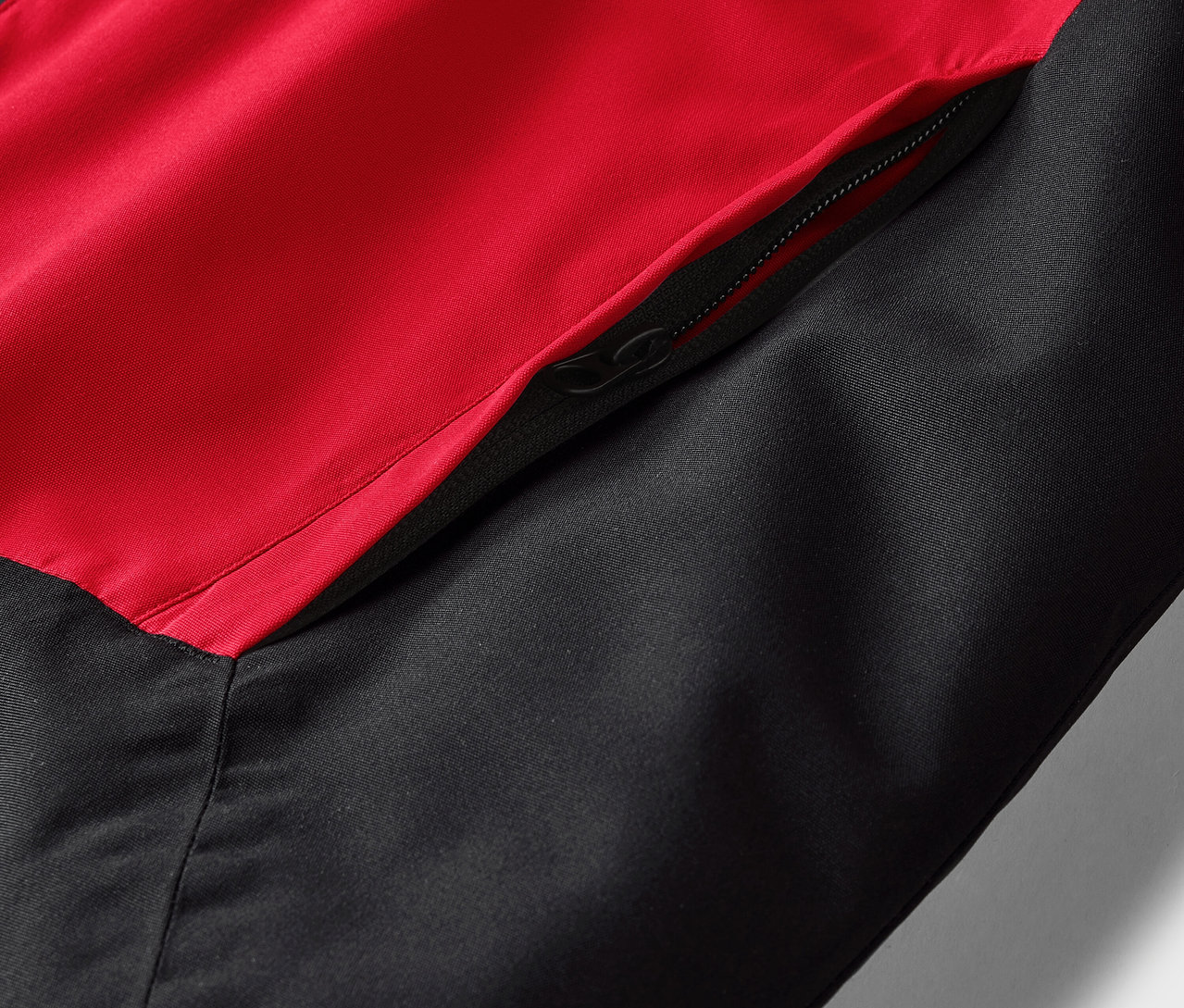Detailaufnahme einer rot-schwarzen Jacke mit Reißverschlusstasche.