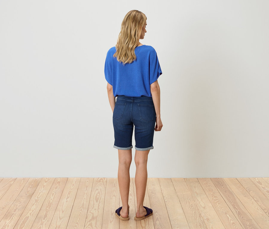 Frau von hinten in blauer Bluse und Jeansshorts.