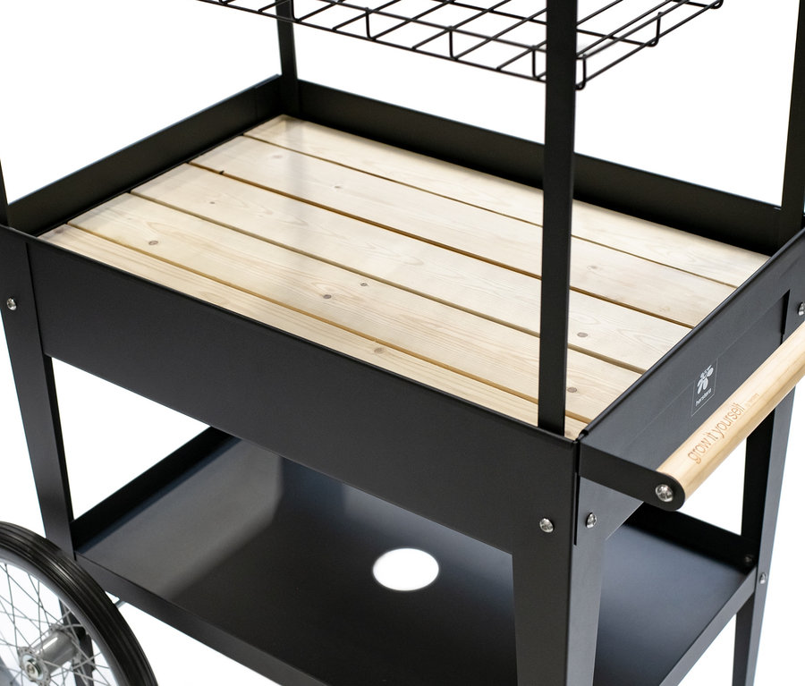 Detailansicht der schwarzen Kräuterfabrik »Urban Expert« mit Holzeinsatz und Rädern.