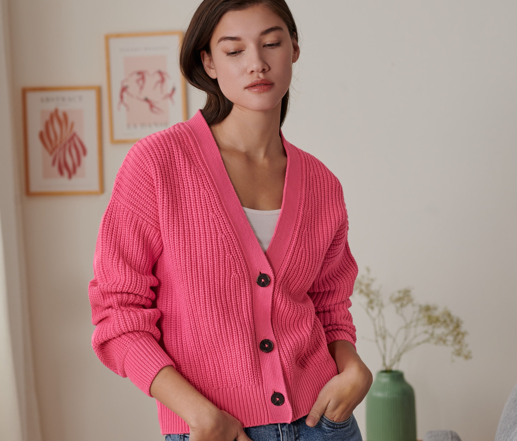 Frau mit Händen in den Hosentaschen der Jeans trägt einen Grobstrick-Cardigan.