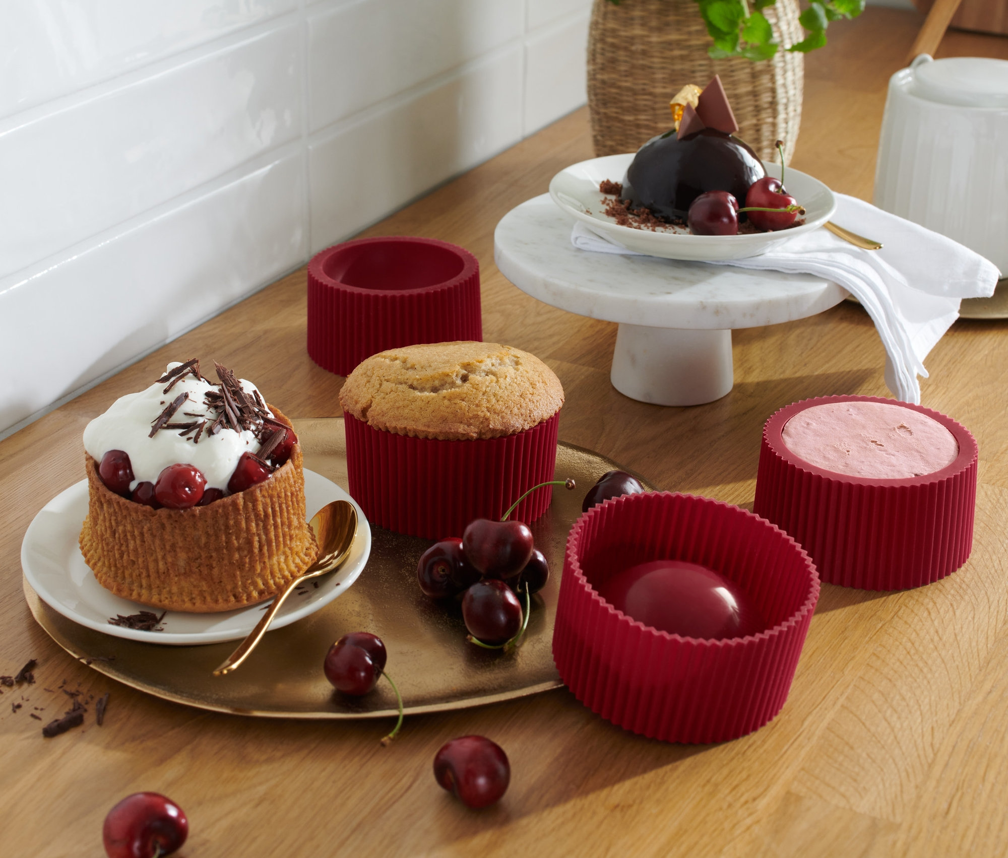 Auf einem Holztisch stehen 4 Dessert-Formen und Teller mit fertigen Desserts.