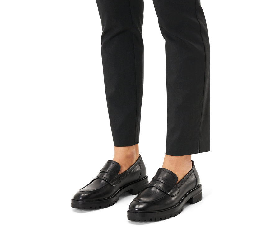 Füße in schwarzen Hosen und Leder-Loafern.