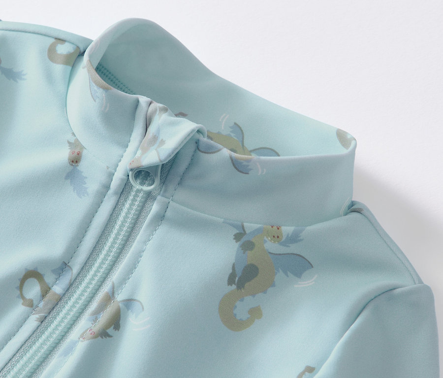 Detailansicht eines blauen Baby-Einteilers mit UV-Schutzfaktor 80 und Drachenmuster mit Reißverschluss.