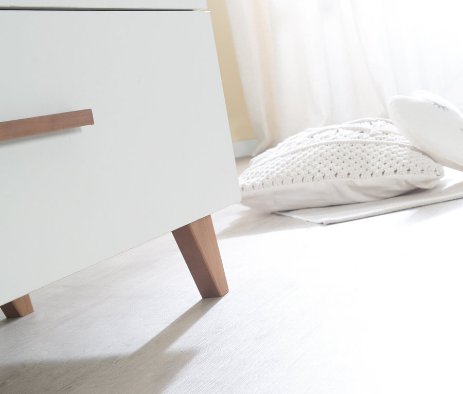 Detailansicht einer weißen roba Wickelkommode »Ole« mit Holzfüßen und Griffen, daneben liegen weiße Kissen.