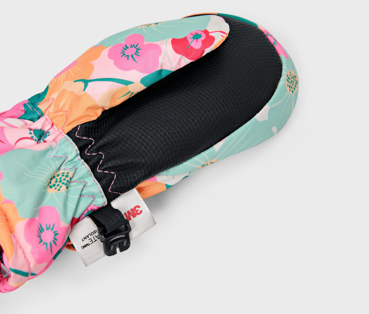 Detail eines bunten Blumenfausthandschuhs mit schwarzem Innenfutter und verstellbarem Riemen.