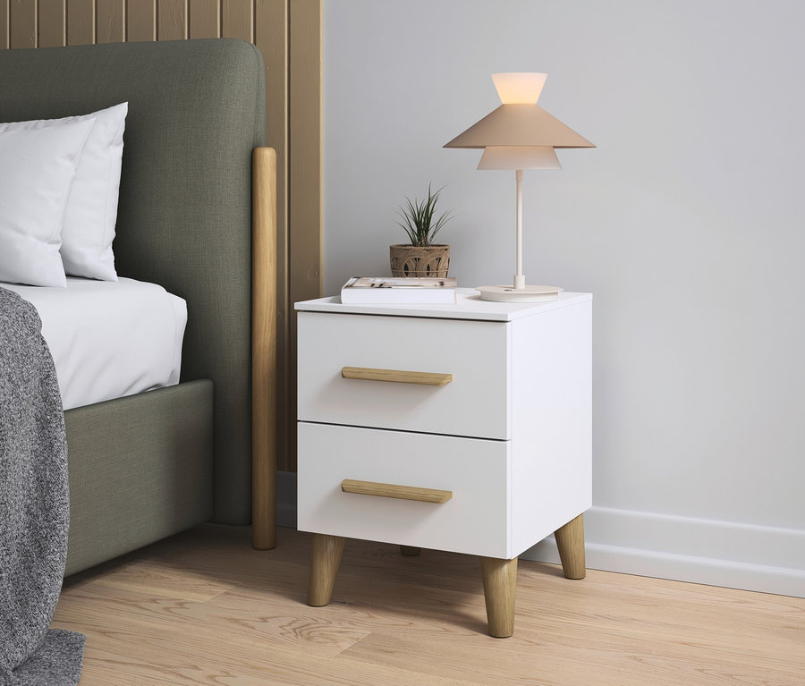 Nachttisch mit Lampe und Pflanze neben einem Bett.